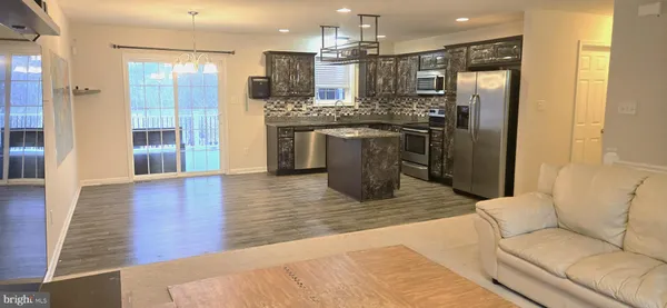 a kitchen with stainless steel appliances kitchen island granite countertop a refrigerator a sink a stove and oven with wooden floor