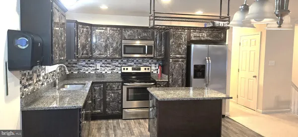 a kitchen with stainless steel appliances granite countertop a sink and a refrigerator