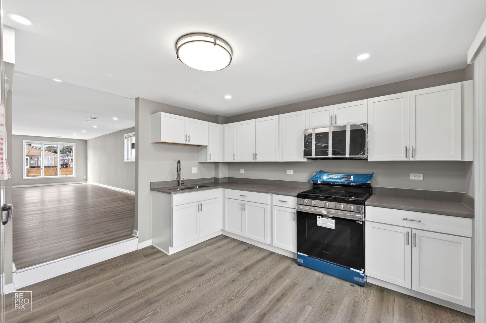 4680 West 83rd Street Chicago, IL 60652 - Photo 6 of 22 a kitchen with stainless steel appliances granite countertop a stove top oven a sink dishwasher and white cabinets with wooden floor