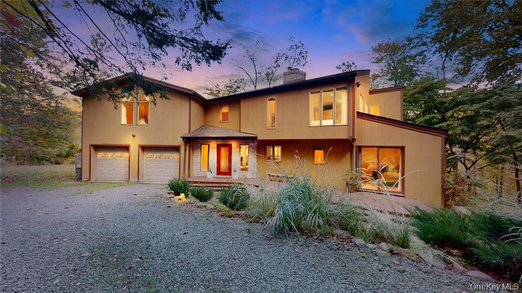 a front view of a house with large trees and plants