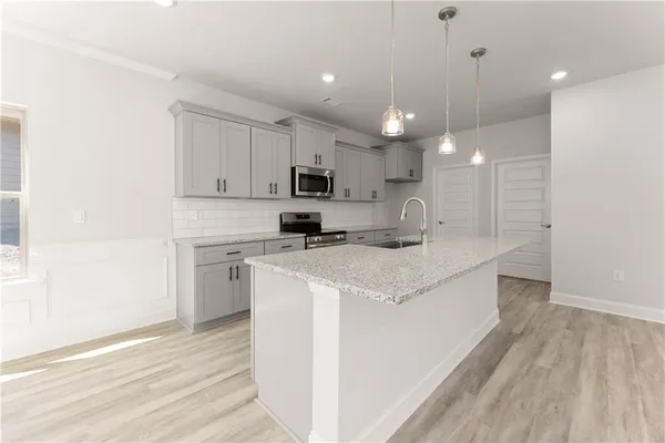 a kitchen with granite countertop a stove top oven a sink a counter space and cabinets