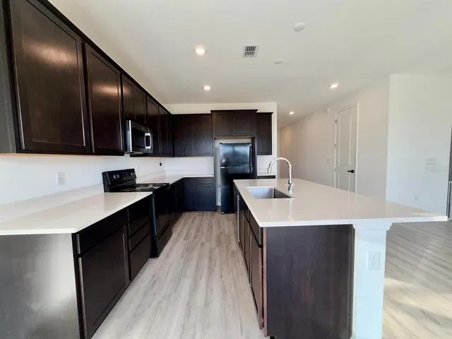 a kitchen with a sink stainless steel appliances a sink cabinets and a wooden floor