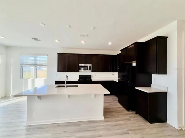 a large kitchen with stainless steel appliances kitchen island granite countertop a large counter top and a stove with wooden floor