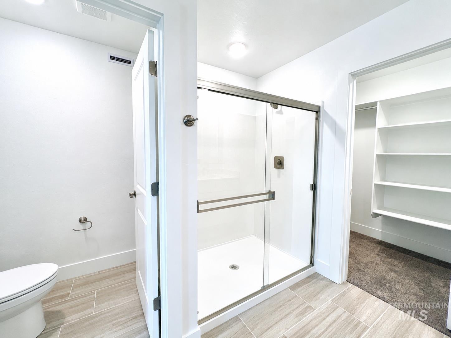 8098 West Fern Street Eagle, ID 83616 - Photo 15 of 22 Full shower enclosure with sliding glass door, modern fixtures, and light-toned tile flooring