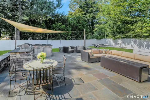 a view of a patio with couches table and chairs under an umbrella with a small pool