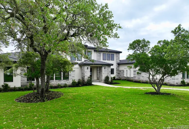 a view of a house with a big yard and large trees