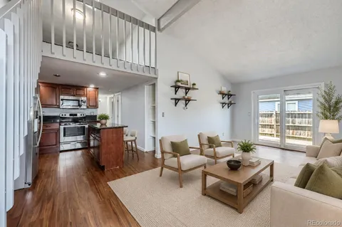 a living room with furniture wooden floor and a kitchen view