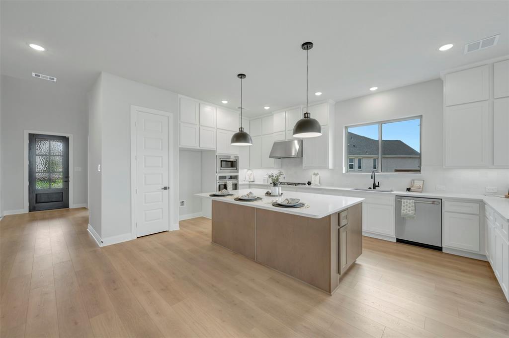 1103 Vista Way Rockwall, TX 75087 - Photo 24 of 26 a large kitchen with kitchen island a sink a stove and a wooden floors