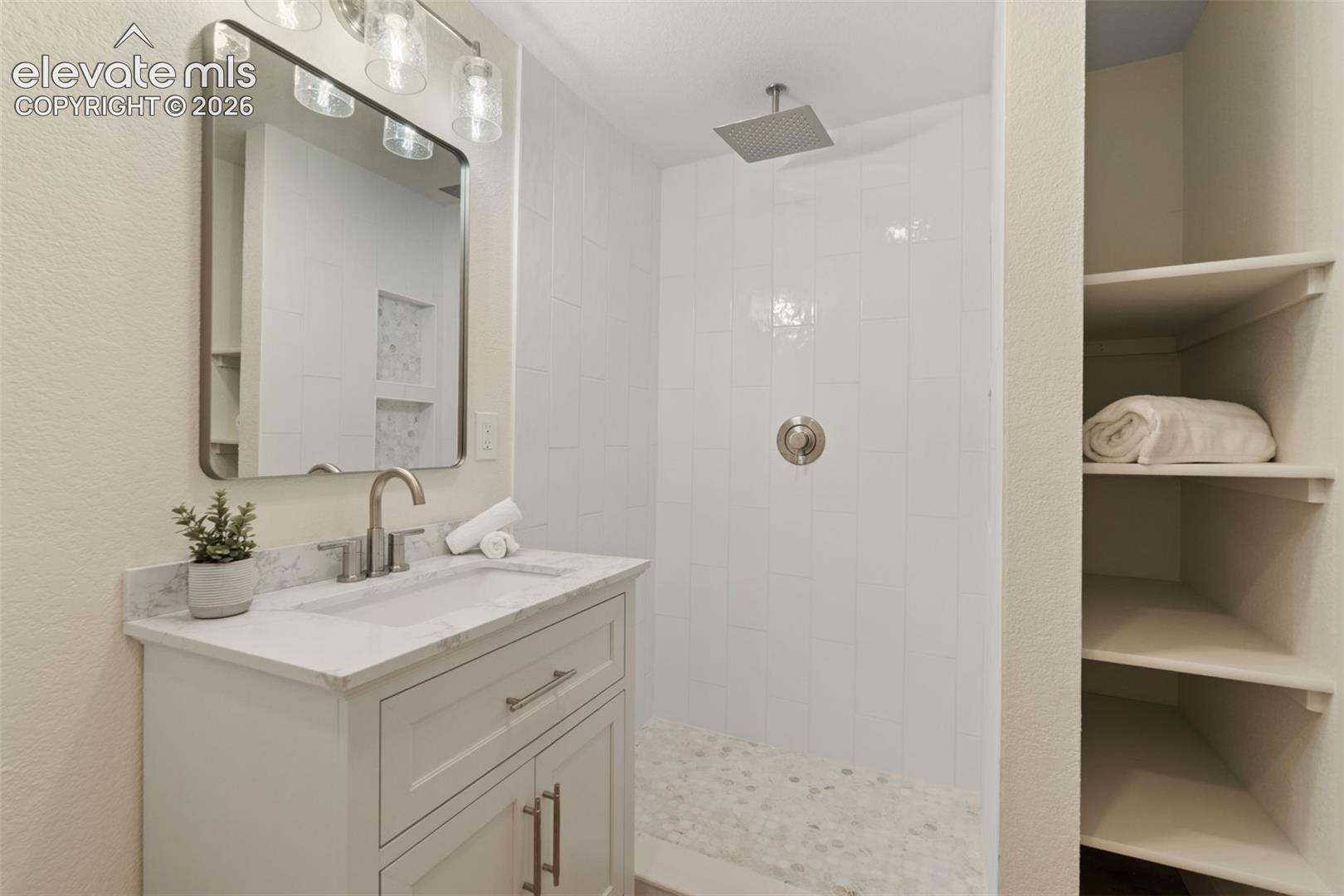 11665 Greentree Road Colorado Springs, CO 80908 - Photo 34 of 43 Full bath with vanity, a walk in shower, and a textured wall