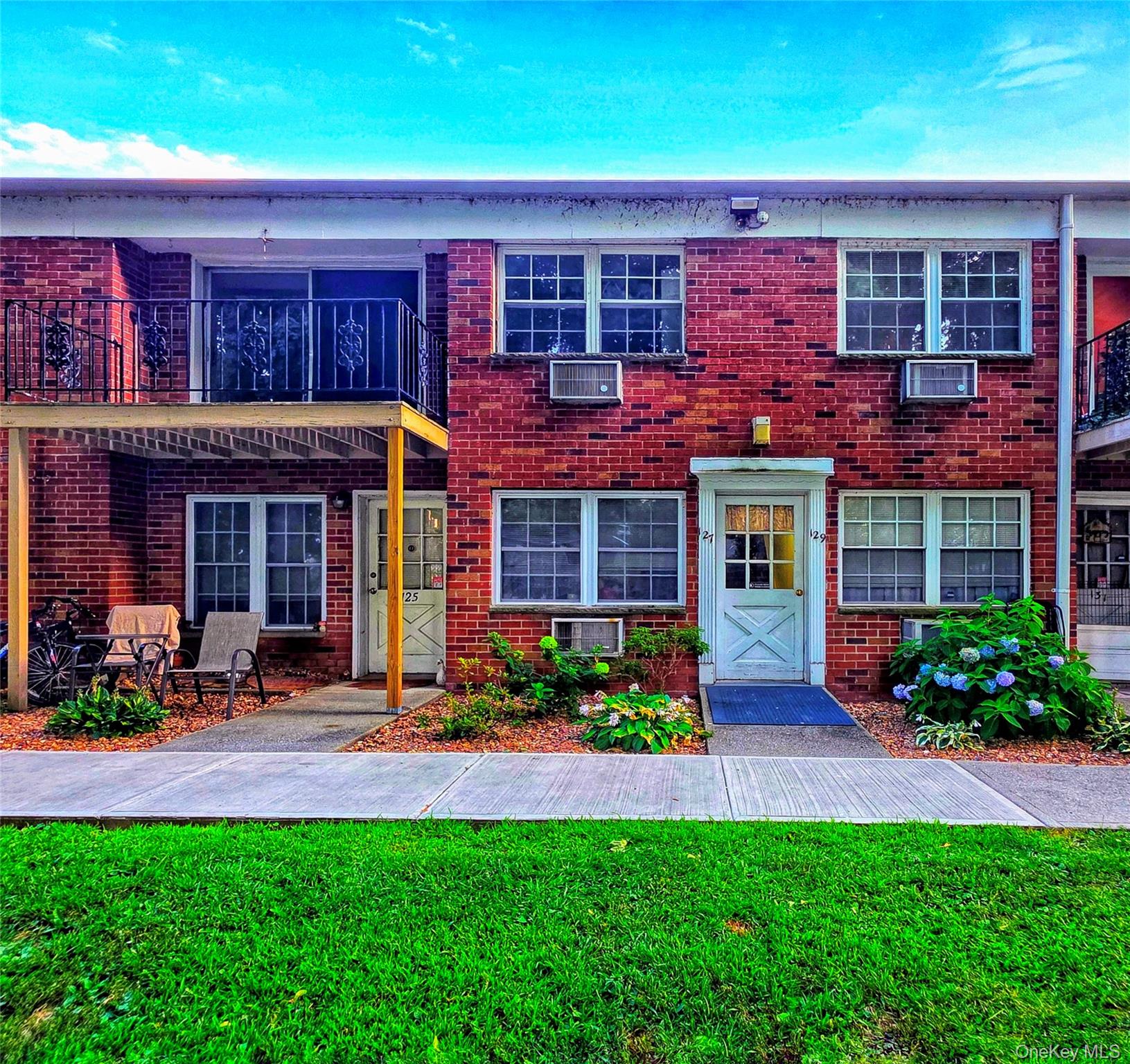 Colonial inspired home with a front lawn, brick siding, and a balcony