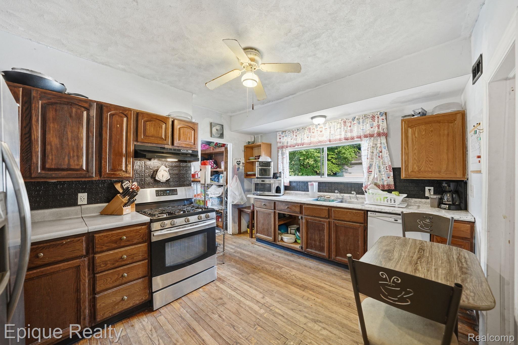 75 East Cicotte Street River Rouge, MI 48218 - Photo 10 of 25 Kitchen featuring wood-finish flooring, dark wood cabinetry, white countertops, stainless steel range, and a ceiling fan