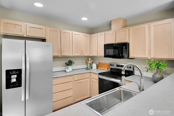 a kitchen with stainless steel appliances white cabinets a sink a stove a refrigerator and a microwave