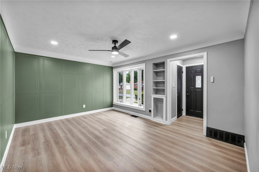 20202 Sumpter Road Cleveland, OH 44128 - Photo 5 of 46 Unfurnished living room featuring built in features, light wood-style flooring, a ceiling fan, a decorative wall, and recessed lighting