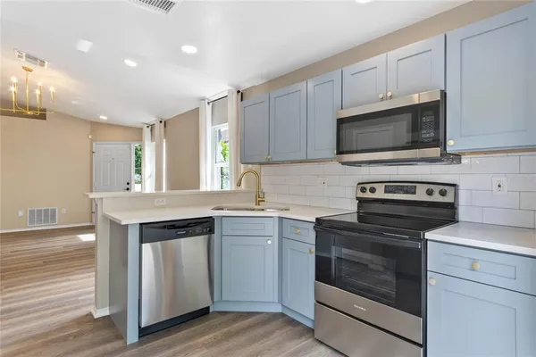 a kitchen with cabinets stainless steel appliances and wooden floor
