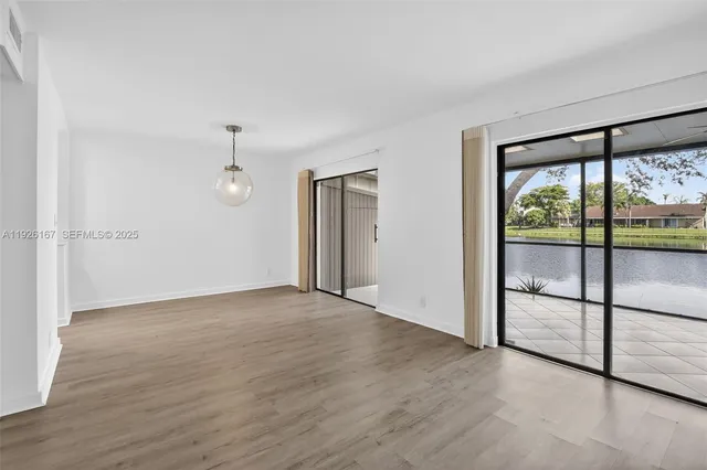 an empty room with sliding glass door and wooden floor