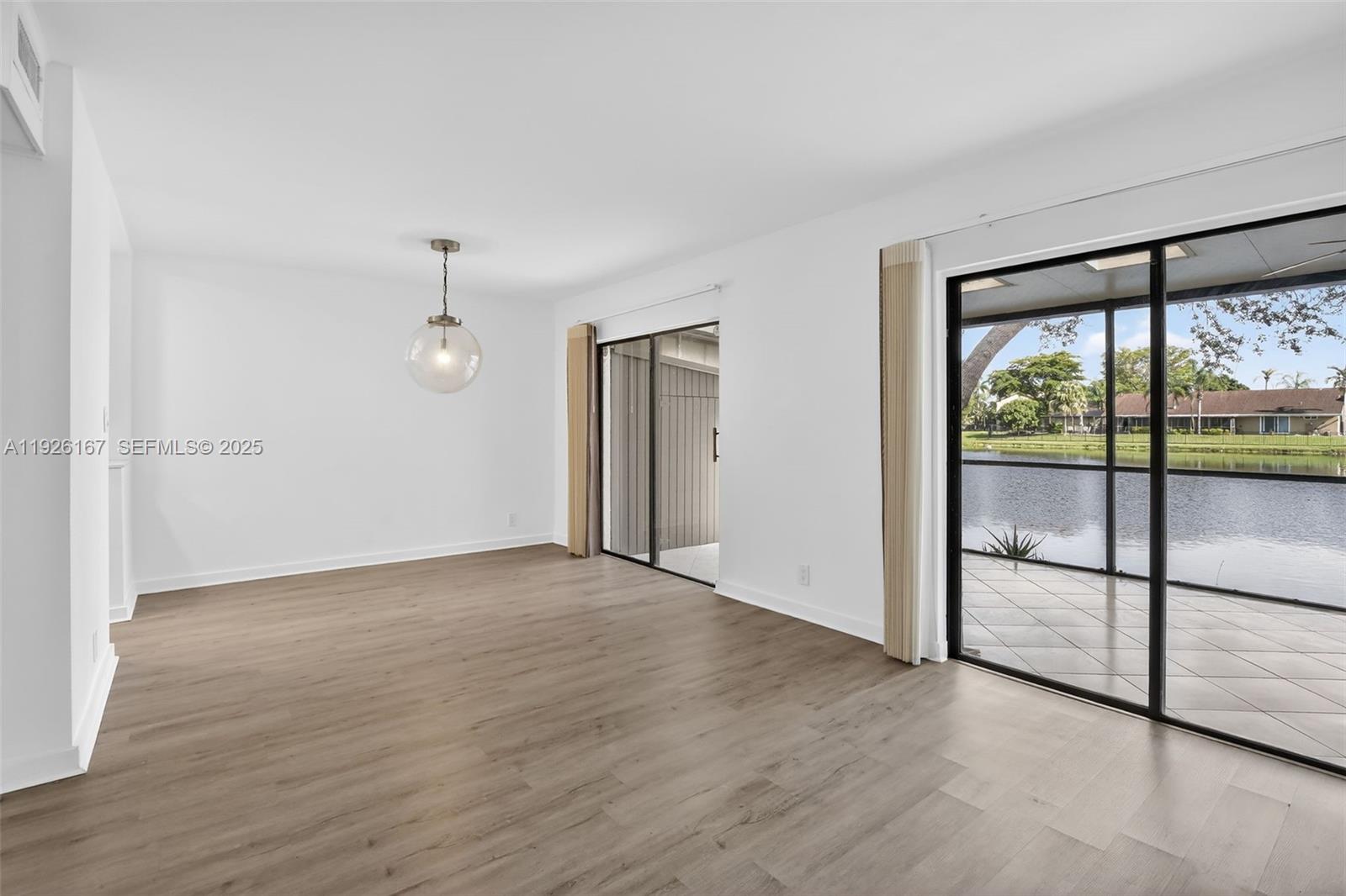 9703 North New River Canal Road, Unit 103 Plantation, FL 33324 - Photo 11 of 32 an empty room with sliding glass door and wooden floor