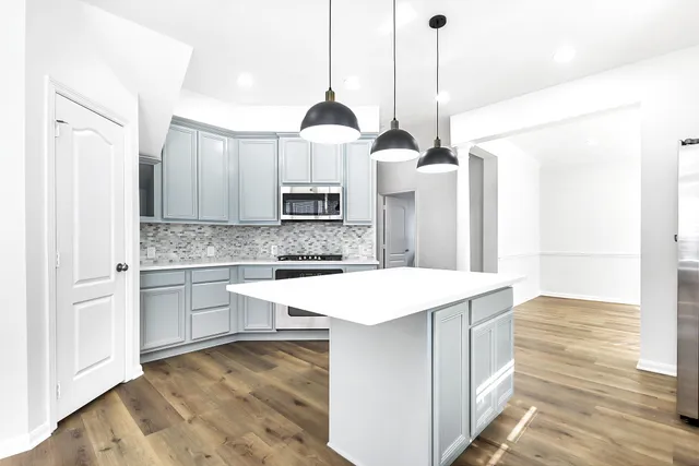 a kitchen with stainless steel appliances kitchen island granite countertop a stove a sink and a refrigerator