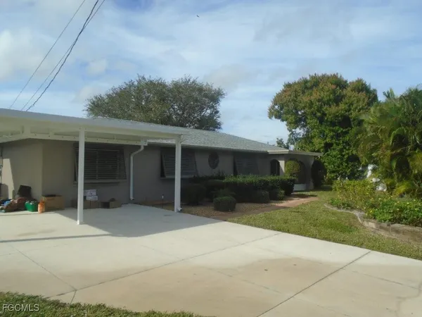 a front view of a house with a garden and trees