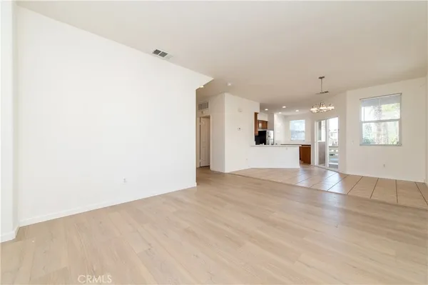 a view of an empty room with wooden floor and a kitchen