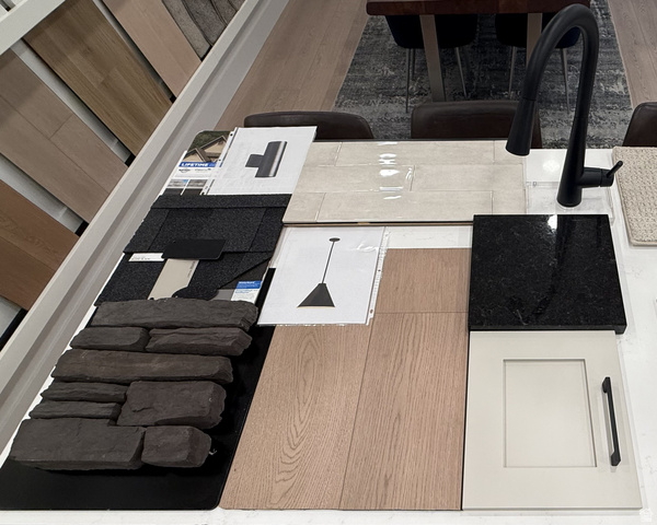 250 West 550 North Smithfield, UT 84335 - Photo 7 of 8 Selection of finishes including dark stone veneer, wood-finish flooring, black shingle roofing, glossy subway tile, and a cream shaker cabinet door with a matte black pull