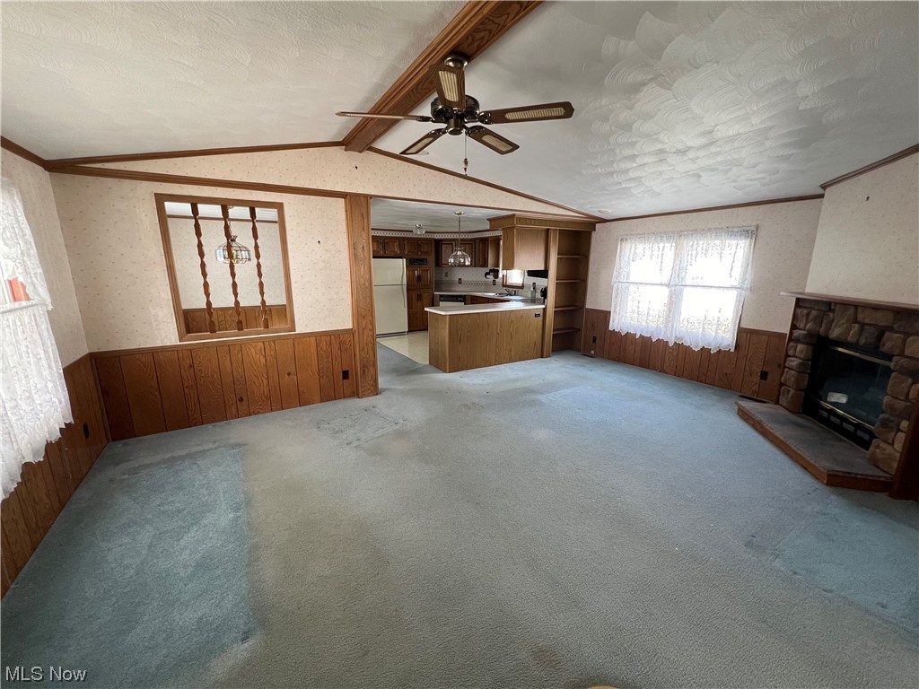 12921 Springfield Road, Unit 3N New Springfield, OH 44443 - Photo 4 of 19 Unfurnished living room with vaulted ceiling with beams, ceiling fan, crown molding, carpet flooring, and a stone fireplace