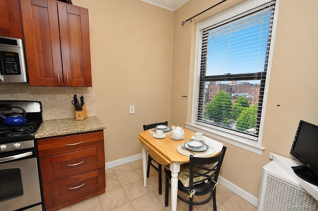143 Garth Road, Unit 5J Scarsdale, NY 10583 - Photo 16 of 47 a kitchen with a wooden table and chairs