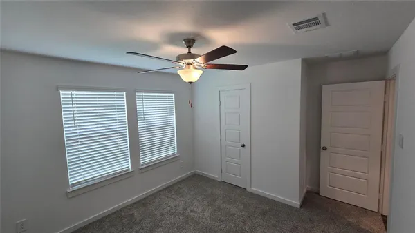 an empty room with windows and fan