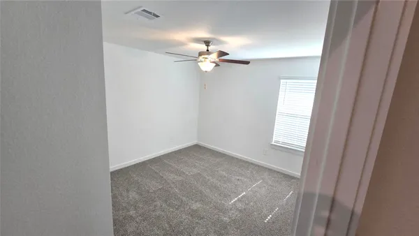 an empty room with windows and fan