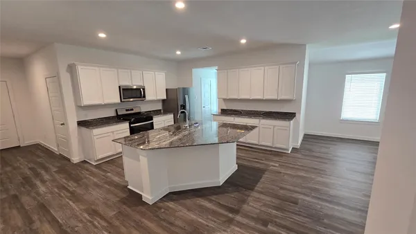 a living room with stainless steel appliances wooden floors and wooden cabinets