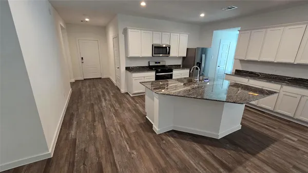 a large kitchen with cabinets wooden floor and stainless steel appliances