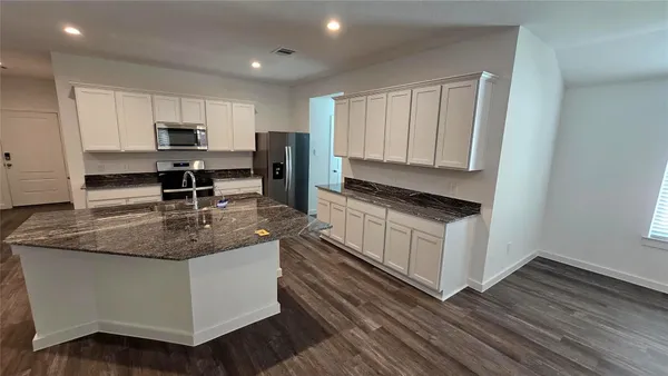 a kitchen with stainless steel appliances granite countertop a stove a sink and white cabinets