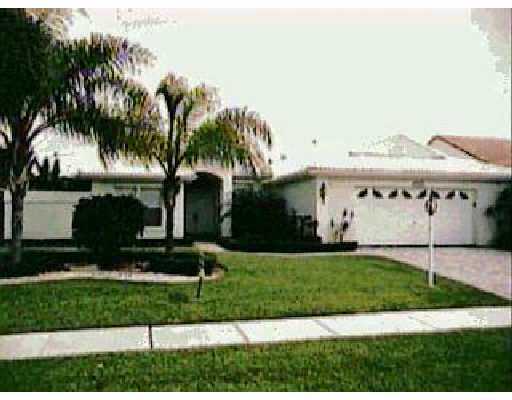 a front view of a house with a garden and palm trees