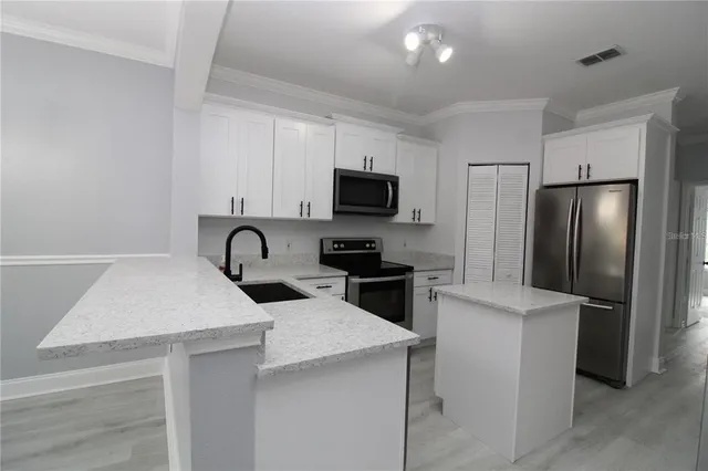 a kitchen with stainless steel appliances kitchen island a refrigerator sink and microwave