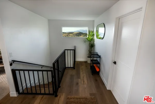 a view of a hallway with wooden floor and stairs