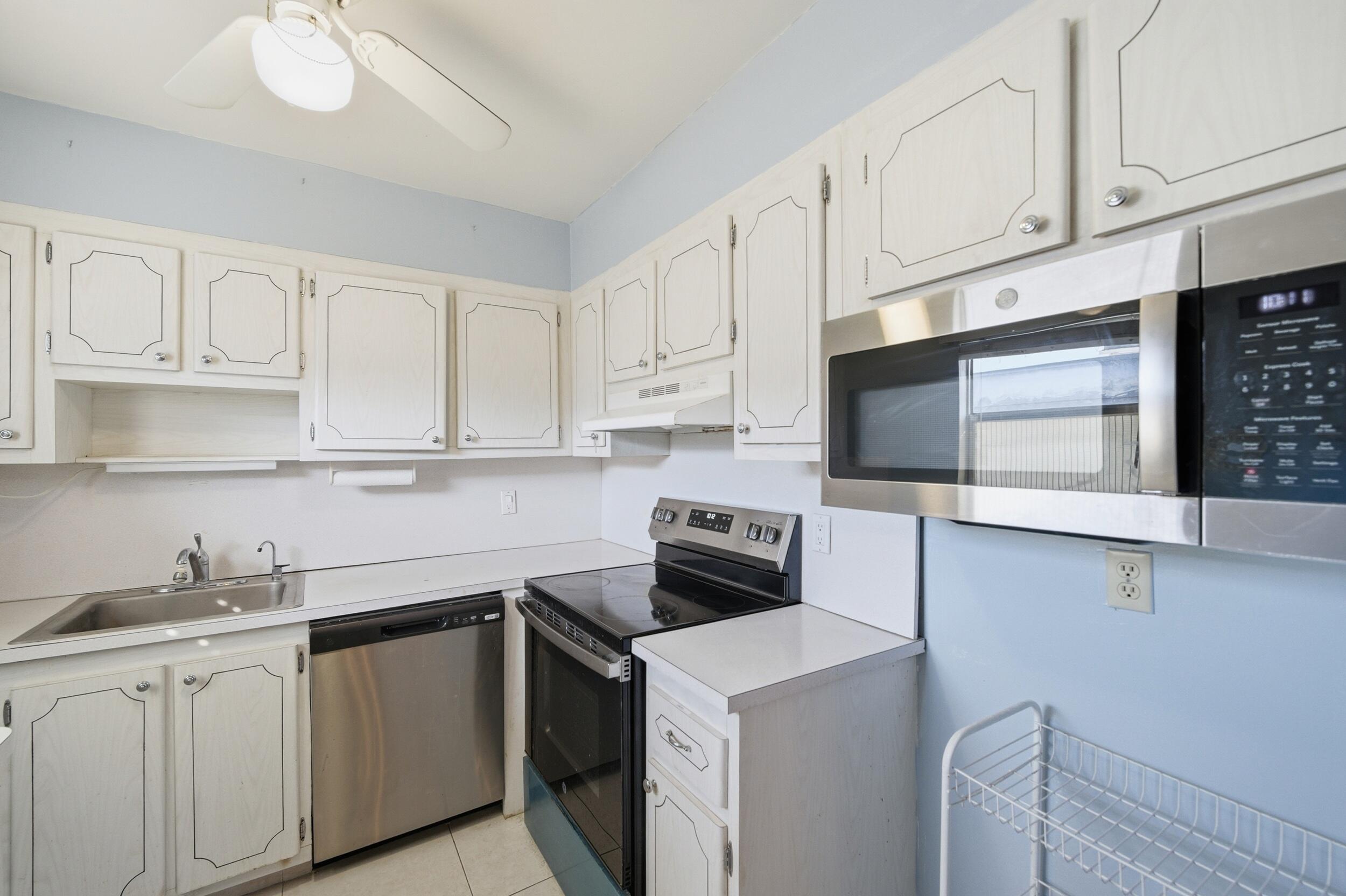 669 Saxony Place Delray Beach, FL 33446 - Photo 27 of 34 a kitchen with white cabinets and white appliances