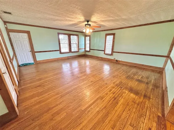 a view of an empty room with a window and wooden floor