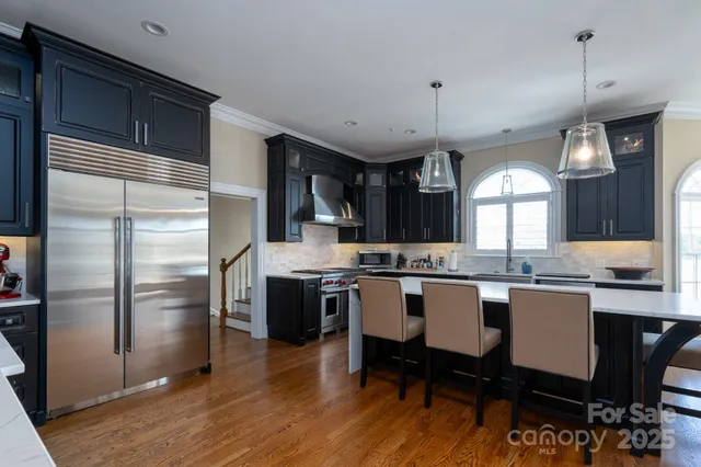 a kitchen with stainless steel appliances a dining table chairs stove refrigerator and cabinets