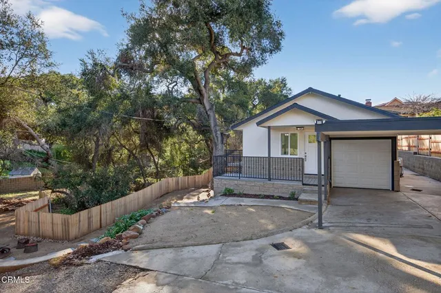a view of a house with a yard and large tree