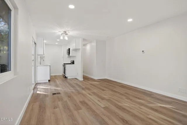 a view of empty room with wooden floor and fan