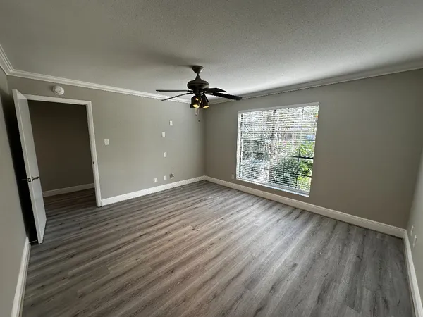 an empty room with wooden floor fan and windows