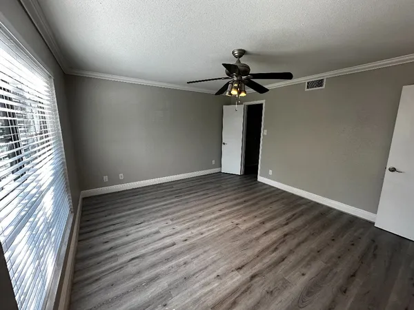 a view of empty room with wooden floor and fan