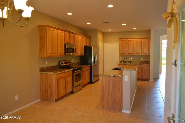 a kitchen with stainless steel appliances granite countertop a refrigerator a stove and a sink