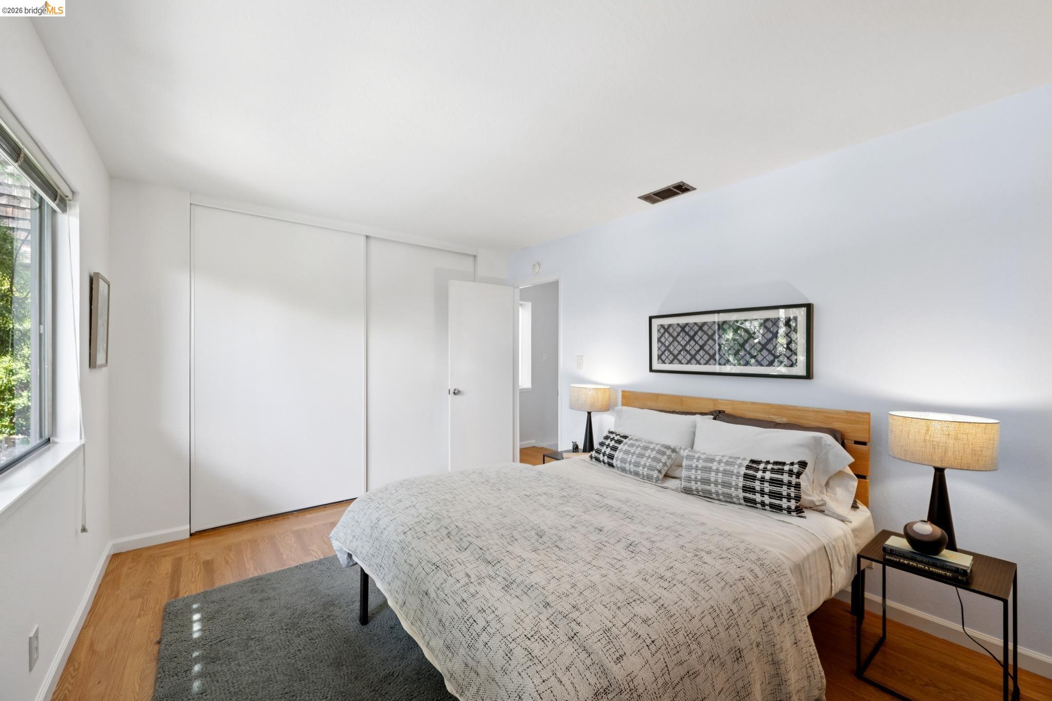 1340 Henry Street Berkeley, CA 94709 - Photo 36 of 52 Bedroom featuring wood-finish flooring, a large window, white walls, and a built-in closet with sliding doors