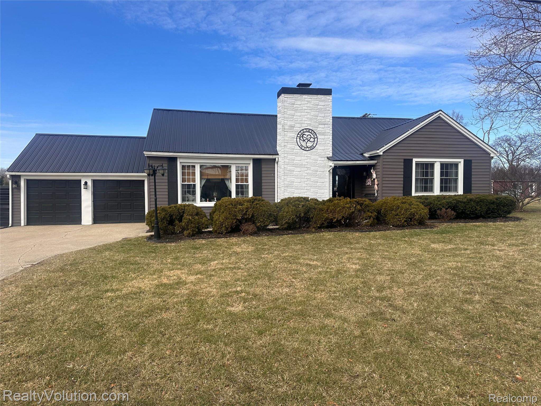 3034 West Oregon Road Lapeer, MI 48446 - Photo 21 of 29 View of front of house featuring a metal roof, a garage, driveway, a front yard, and a chimney