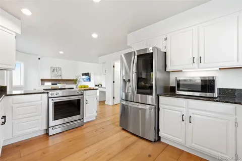a kitchen with cabinets stainless steel appliances and wooden floor
