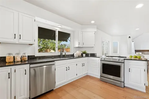 a kitchen with granite countertop white cabinets and white appliances