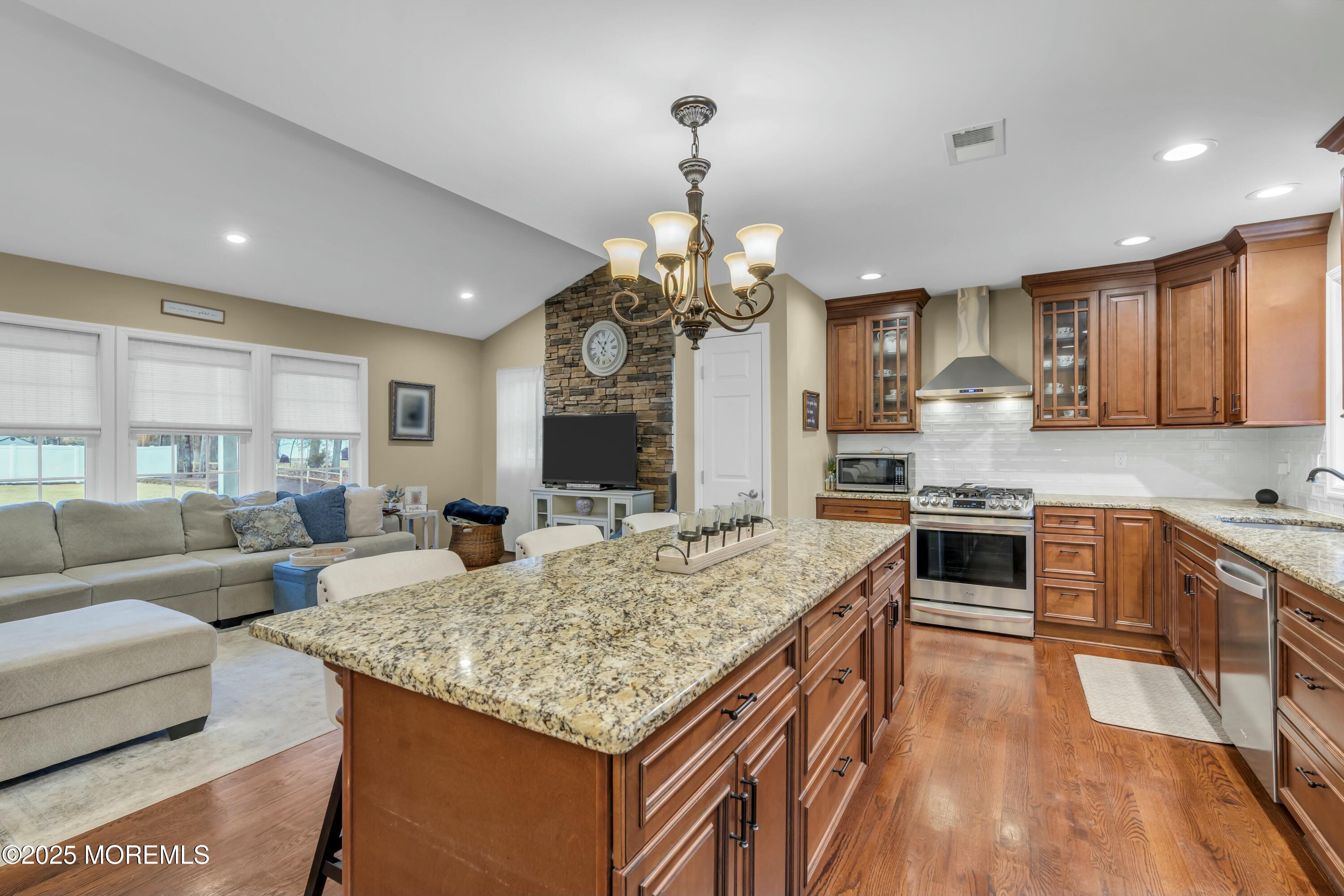 16 Glenarden Drive Howell, NJ 07731 - Photo 32 of 63 a kitchen with kitchen island granite countertop a stove top oven a sink dishwasher a dining table and chairs with wooden floor
