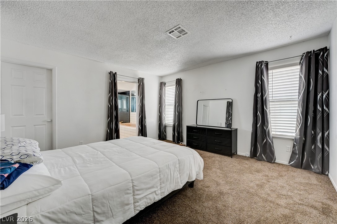 1751 East Reno Avenue, Unit 228 Las Vegas, NV 89119 - Photo 19 of 39 A comfortable bedroom features plush carpeting and a clear view into an adjoining bathroom with a soaking tub.