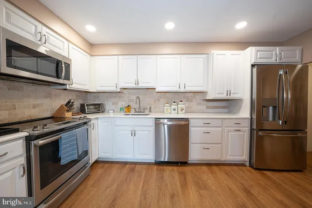 a kitchen with granite countertop white cabinets and stainless steel appliances