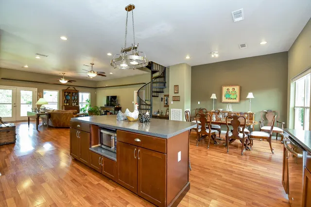 a kitchen with stainless steel appliances granite countertop a refrigerator a sink dishwasher a dining table and chairs with wooden floor